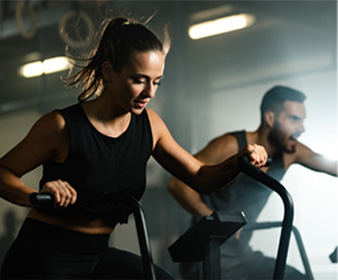 Two people working out vigorously on ellipticals