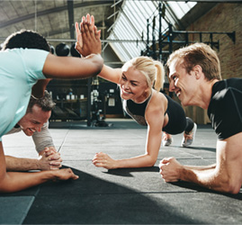 Four people doing planks and two of them are giving each other a high five